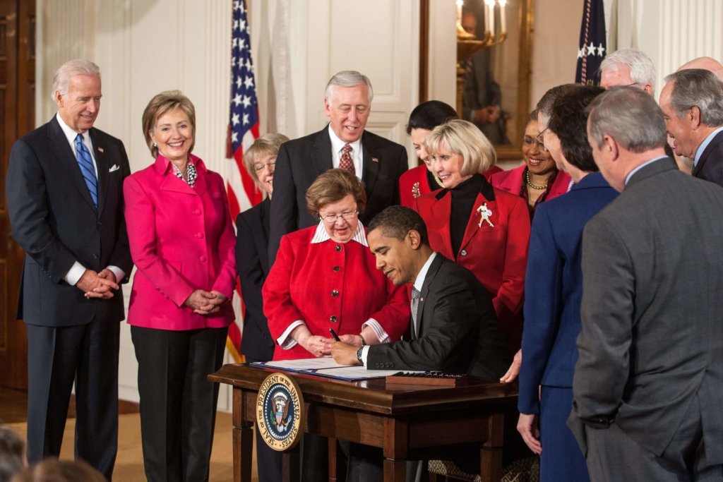 A photo of Barack Obama signing legislation that enforces/encourages equal pay.