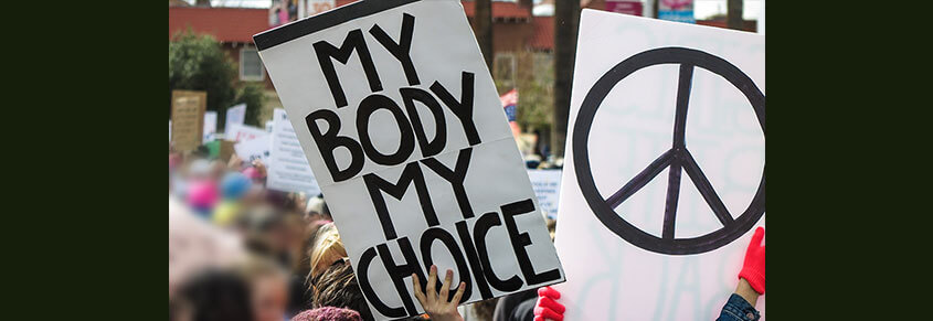 A photo from a pro-choice protest with someone carrying a sign that says, "My Body. My Choice."