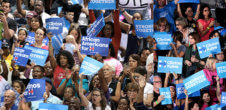 Photo from a Hillary Clinton rally where people are holding up posters that say "Clinton Kaine" and "African Americans for H"