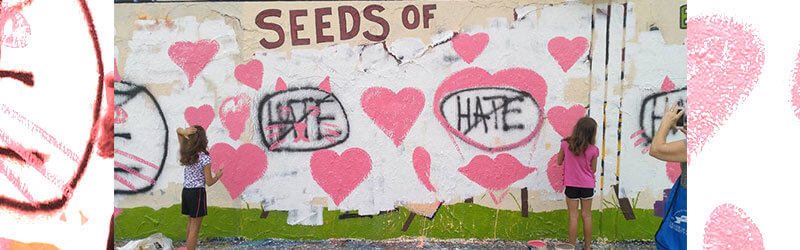 A photo of graffiti that says "Seeds Of" and there are many hearts, and the word "hate" is crossed out.