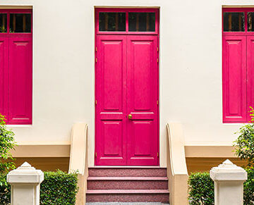A photo of a tan house. The windows and door are hot pink.