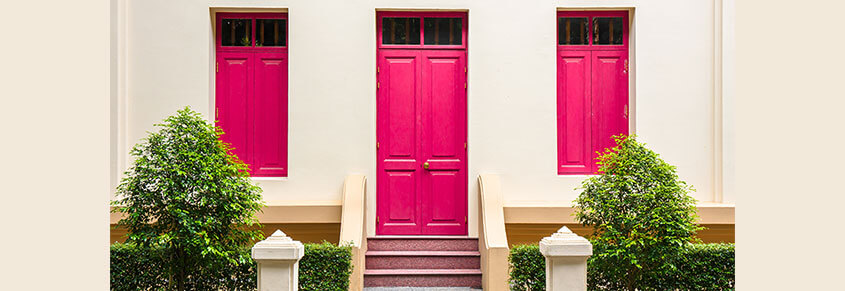 A photo of a tan house. The windows and door are hot pink.