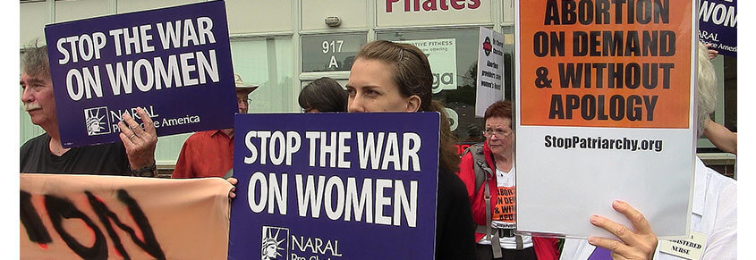 A photo of a pro-choice protest with people holding signs with messages like, "Stop The War on Women" and "Abortion On Demand & Without Apology"