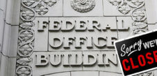 A photo of a Federal Office Building with a "Sorry, we're closed" sign on it.
