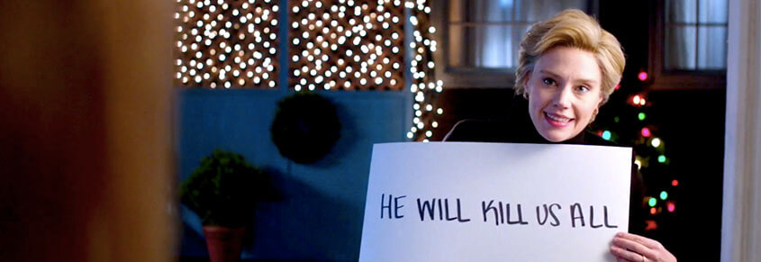 A photo of Kate McKinnon holding up a sign that says, "He Will Kill Us All"