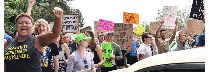 A photo from a protest with signs with messages like "Diversity Makes Us Stronger," "Muslims Against White Supremacy, Racism, & Ant-Semitism