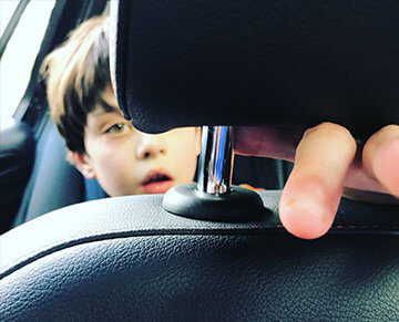 A photo of a young white boy in the back of a car.