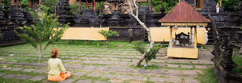 A photo of a woman meditating in a courtyard