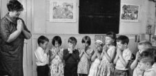 A photo of a teacher praying with her young students.
