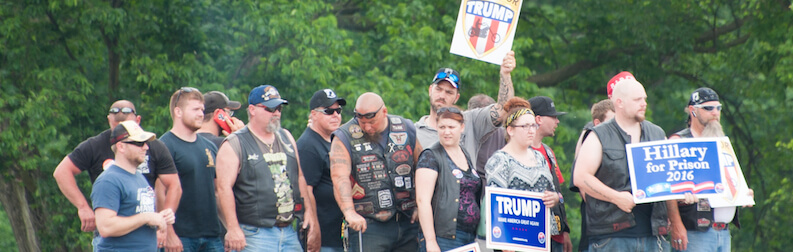 A photo of Trump supporters with signs like "Hillary For Clinton 2016"