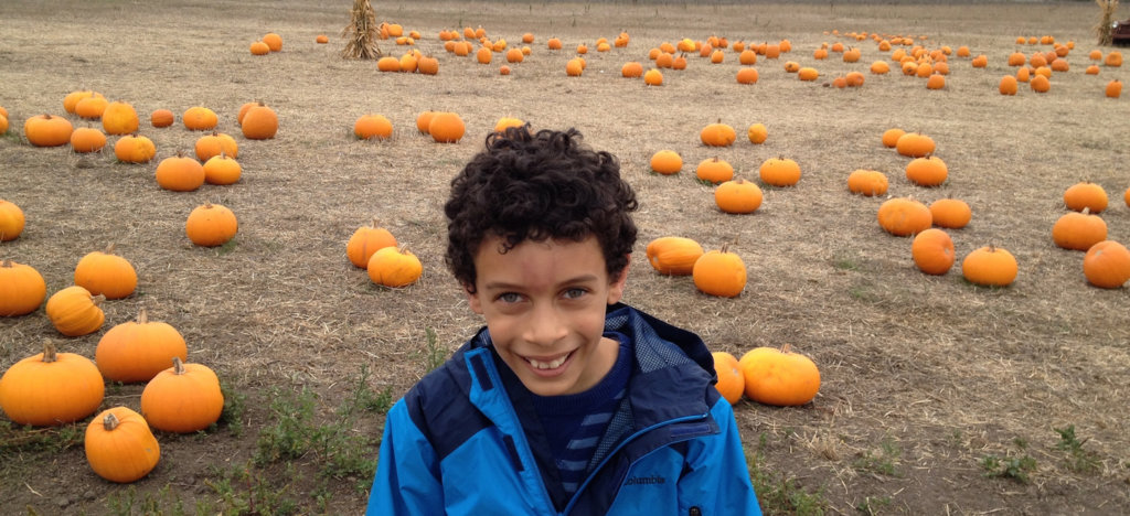 A photo of a biracial child at a pumpkin patch