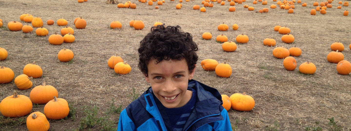 A photo of a biracial child at a pumpkin patch