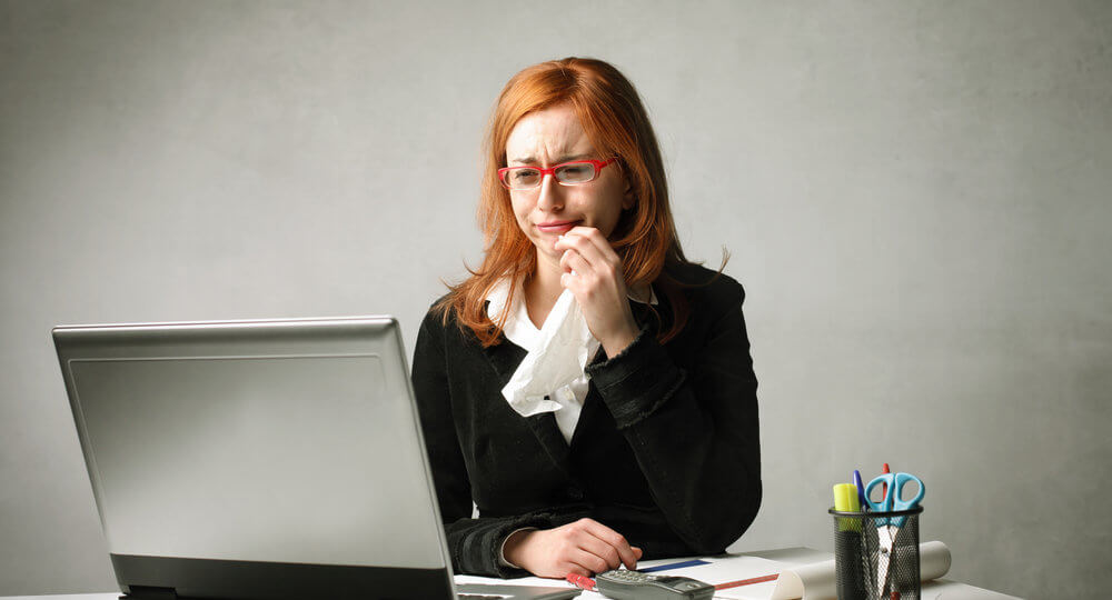 A photo of a white woman crying in front of her computer