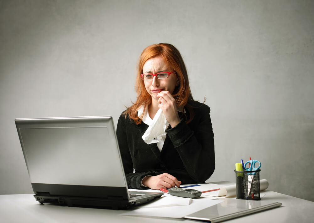 A photo of a white woman crying in front of her computer