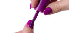 A photo of someone painting their nails purple.