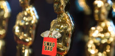 A photo of Oscars. In front of one, there is a swag bag with money in it.