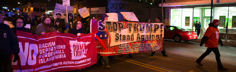 An anti-Trump protest with signs like "Stop Trump! Stand Against Racism, Anti-Immigrant and Anti-Muslim Attacks."