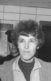 A photo of Valerie Solanas after she had been arrested. A police officer is in the background.