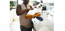 A photo of a Black woman holding laundry.