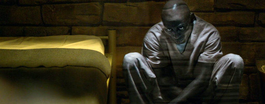 A still from the Black Mirror episode “Black Museum,” featuring a Black man sitting on the ground.