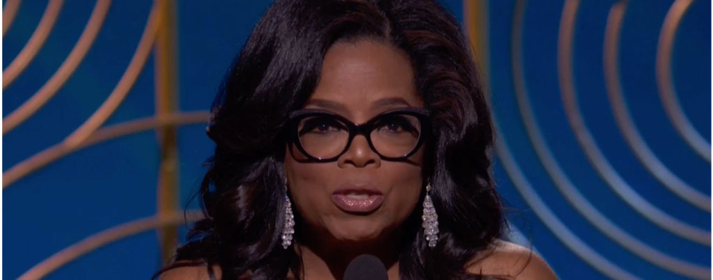 Oprah Winfrey speaking on stage at the Golden Globes