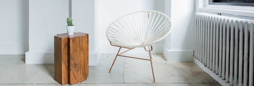 A photo of a chair and a table with a plant in it.