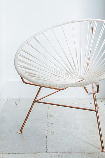 A photo of a chair and a table with a plant in it.