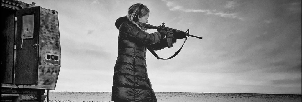 A photo of a white woman shooting a machine gun in a desert