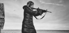 A photo of a white woman shooting a machine gun in a desert