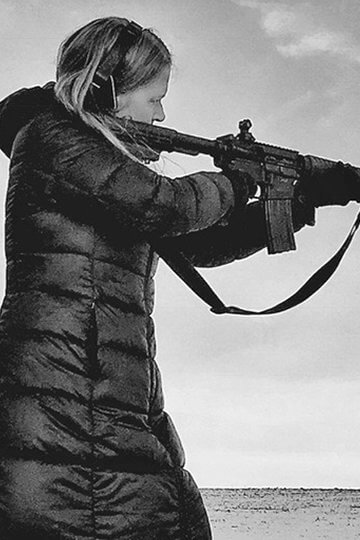 A photo of a white woman shooting a machine gun in a desert
