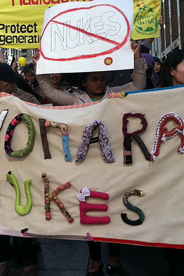 A photo of a protest. A sign that says 'Sayonara Nukes" is mostly visible.