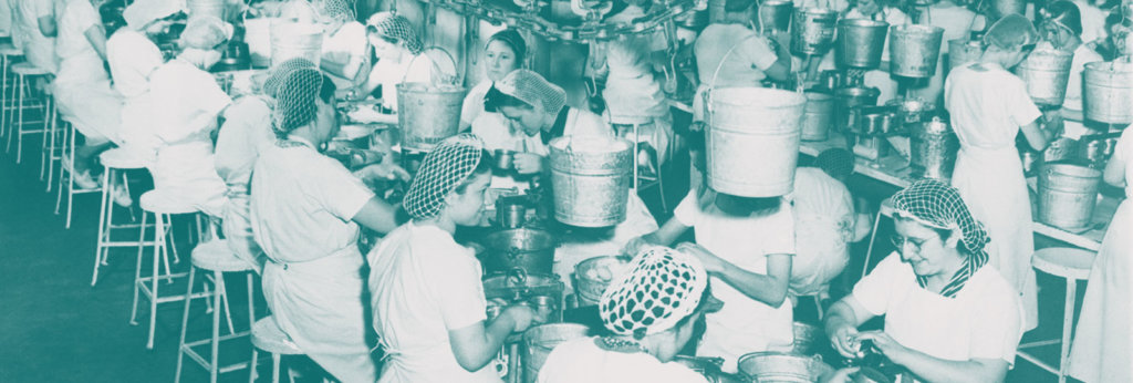 A photo of women working at a factory with nets in their hair.