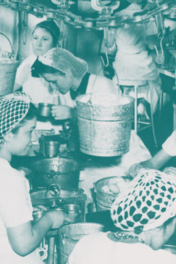 A photo of women working at a factory with nets in their hair.