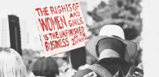 A photo from a protest with a sign that says, "The Rights of Women and Girls is the Unfinished Business of the 21st Century"