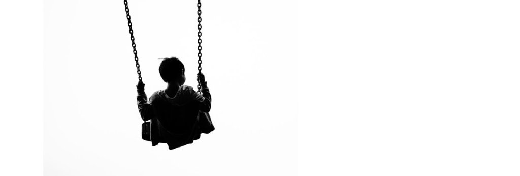A black and white photo of a kid on a swing