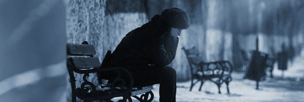 A photo of a woman sitting outside on a bench with her hands over her ears