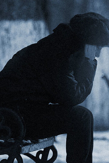 A photo of a woman sitting outside on a bench with her hands over her ears