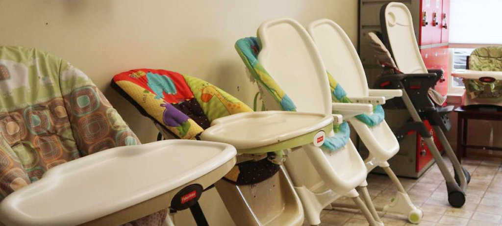 A photo of chairs used for babies against a wall.