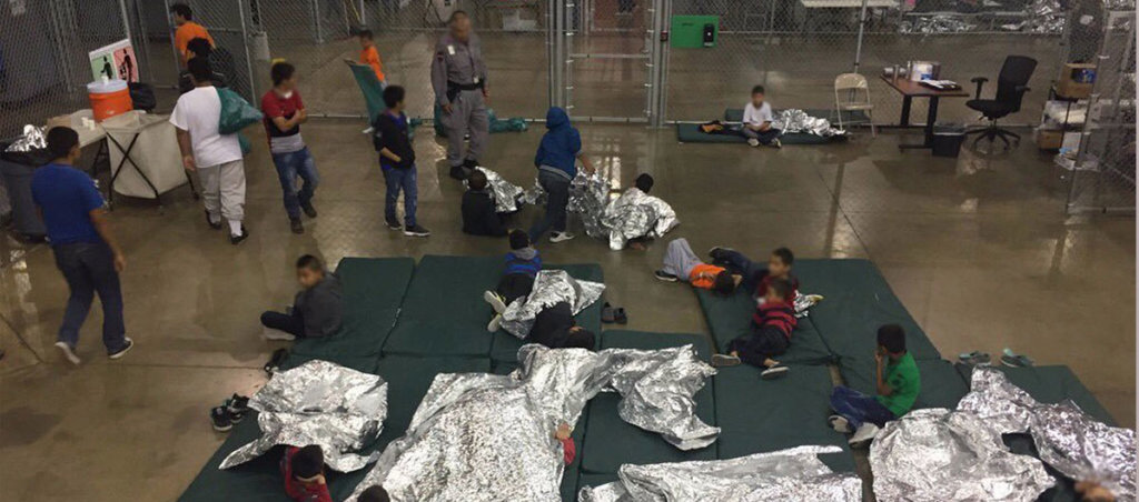 A photo of migrant children lying down in cages.