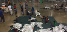 A photo of migrant children lying down in cages.