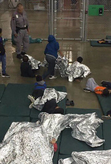 A photo of migrant children lying down in cages.