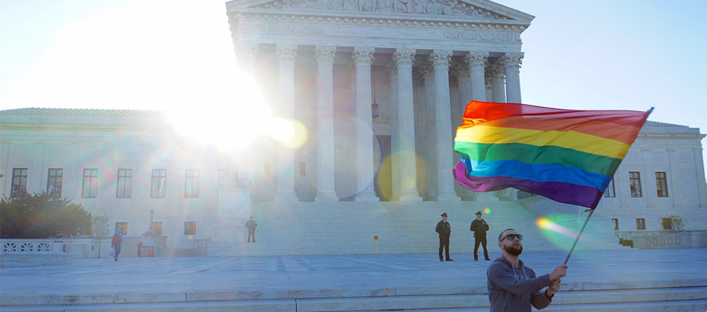 Someone waiving a Pride Flag in front of the Supreme Court