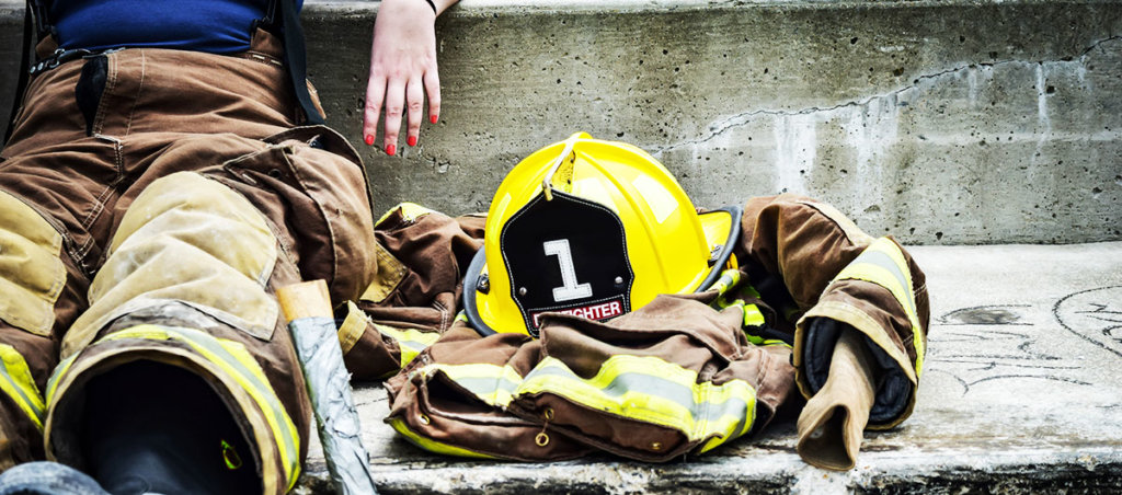 A photo of someone in a firefighter's uniform sitting down. We only see their midsection.