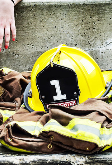 A photo of someone in a firefighter's uniform sitting down. We only see their midsection.