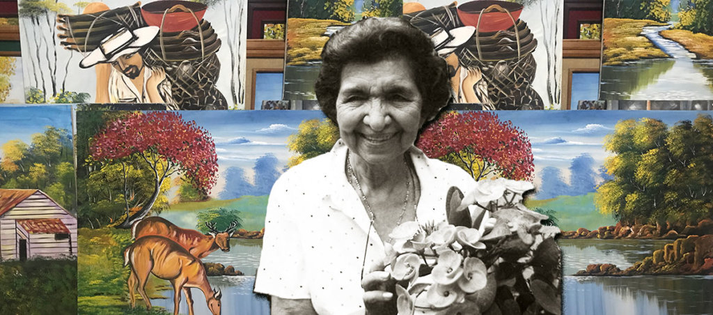 A photo of María Alva Consuelo Guevara Herrera de Rodriguez with paintings in the background.