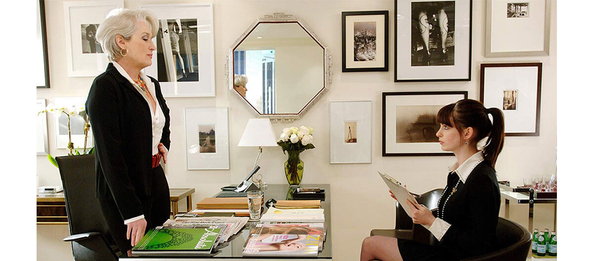 A still of Meryl Streep standing up and Anne Hathaway sitting down in "The Devil Wears Prada" in an office setting.