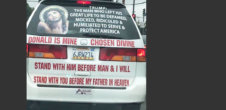A photo of the back of the car that has a picture of Jesus Christ on it, as well as the text "Trump: The man who left his great life to be defamed, mocked, ridiculed, humiliated to serve & protect America. Donald is mine chosen divine. Stand with him before man & I will stand with you before my father in heaven."