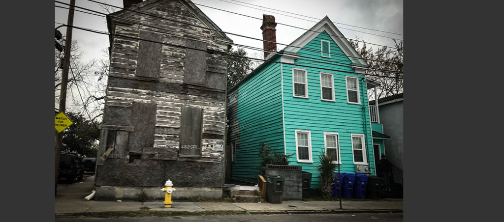 A photo of two houses. One of the houses has its windows covered.