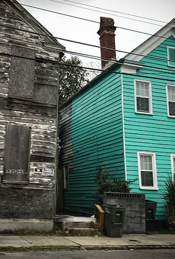 A photo of two houses. One of the houses has its windows covered.