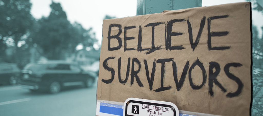 A photo of a sign that says "Believe Survivors"